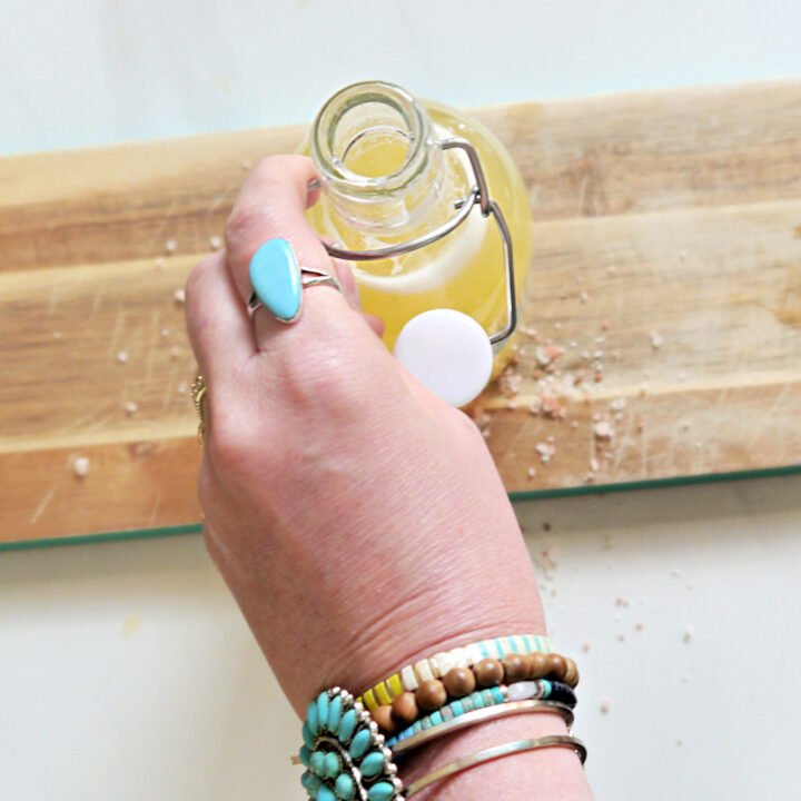 A Hand with Turquoise jewelry touching a flip top bottle of Homemade Electrolyte Drink