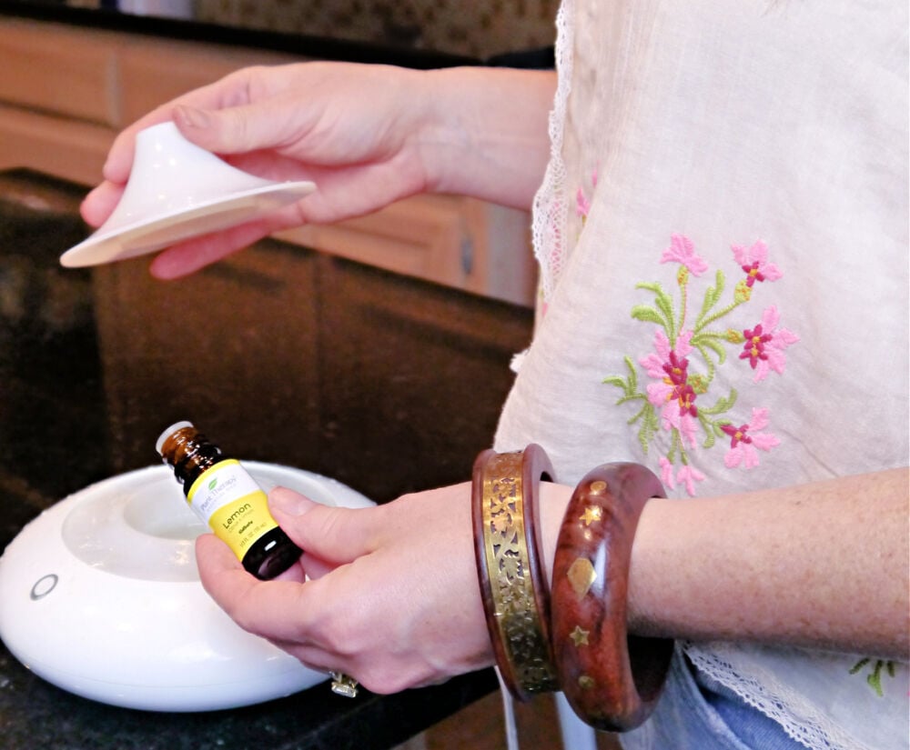 A woman pouring lemon essential oil into a diffuser