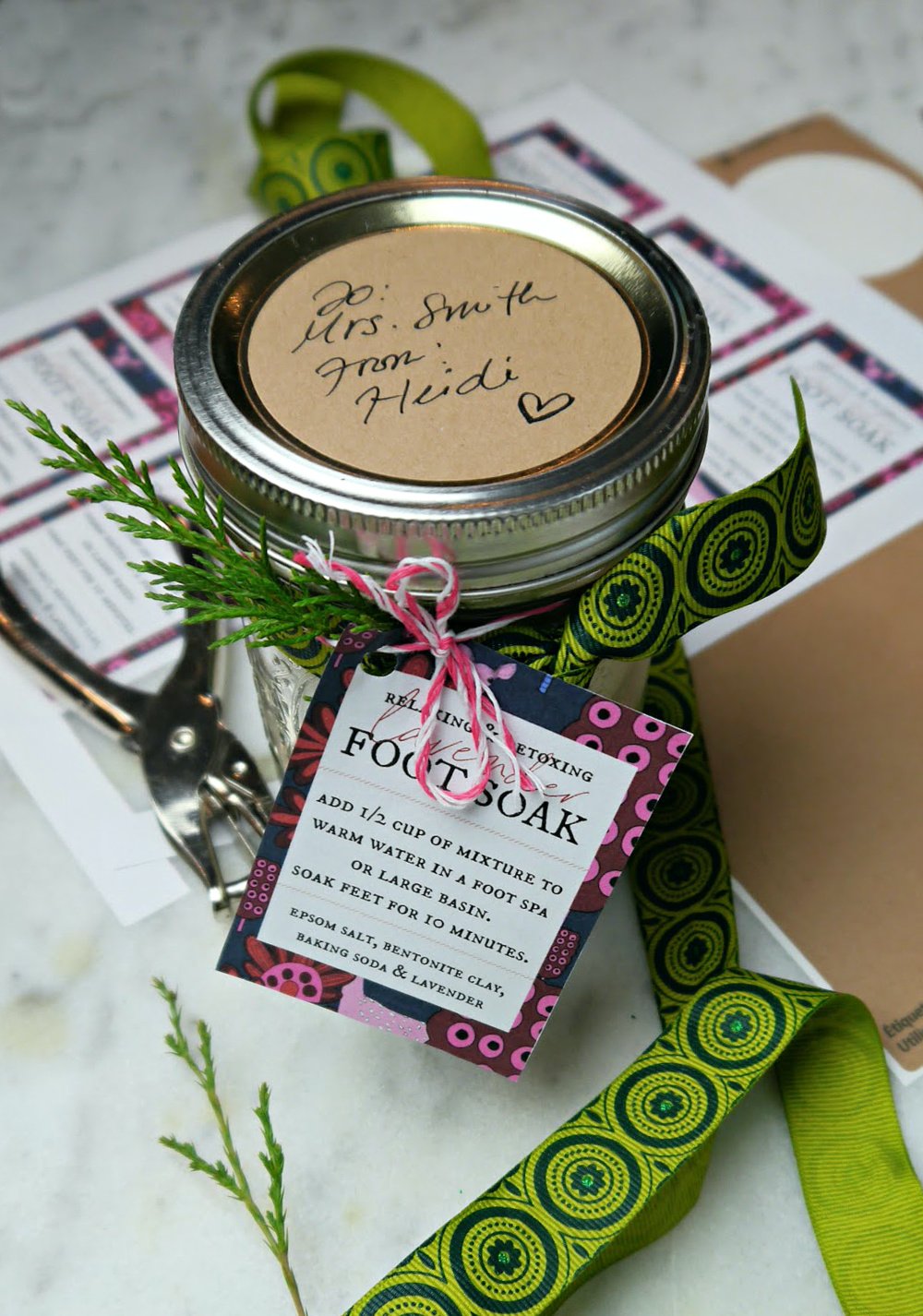 Jar with foot soak and a tag with ribbons and a pine sprig.