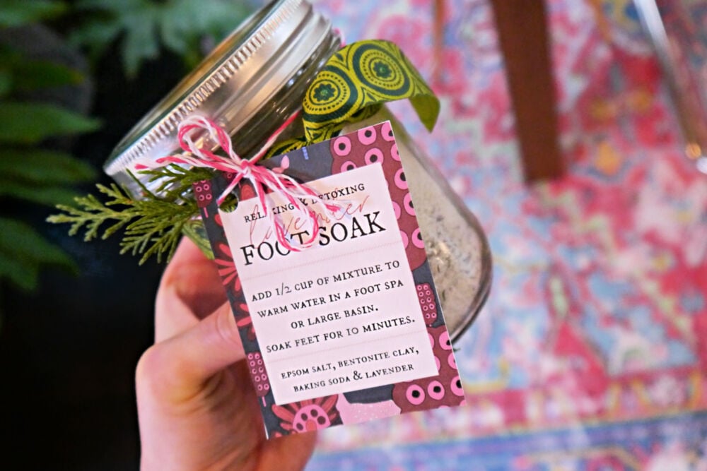 Hand holding a jar of foot soak with tag and ribbon.