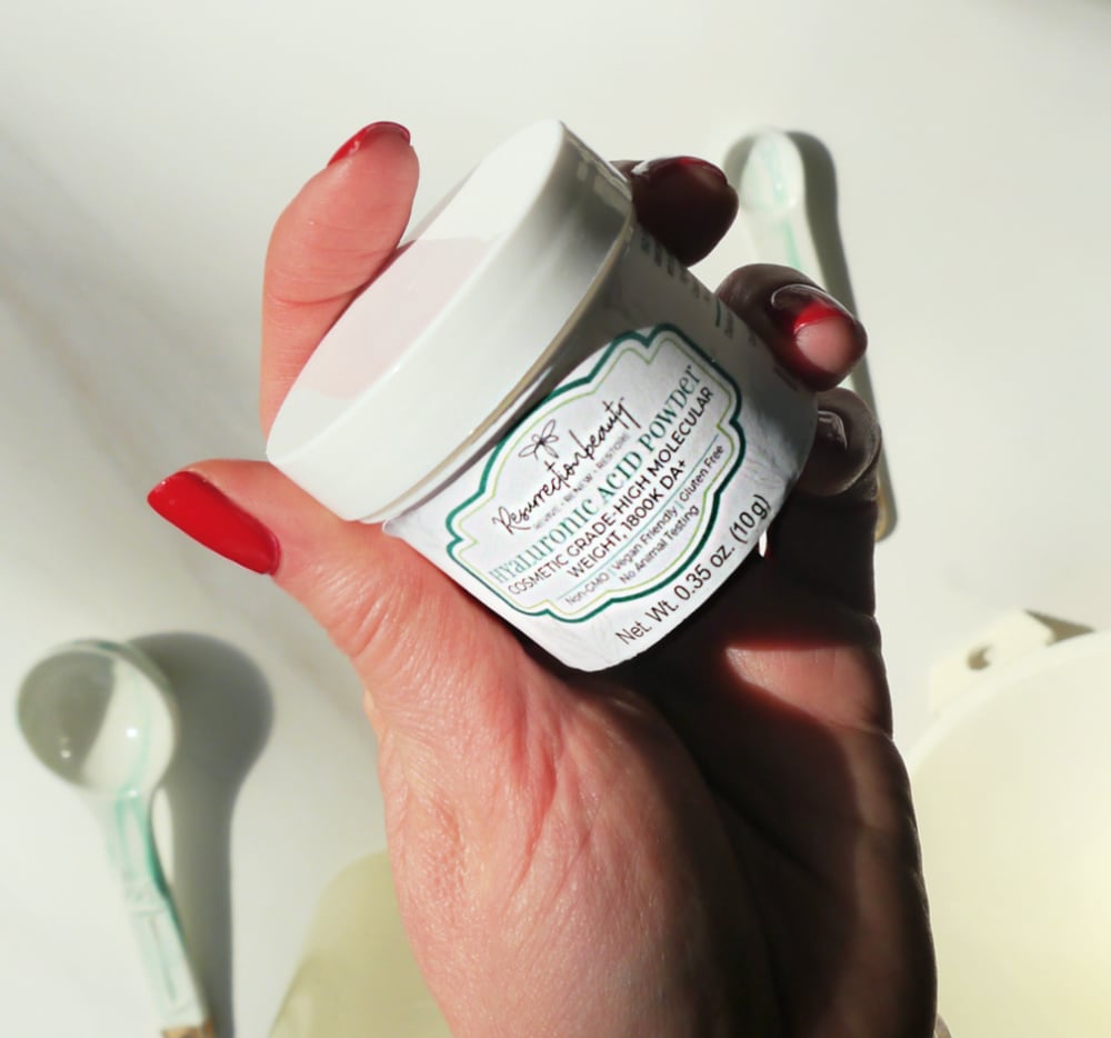 Hand holding a jar of hyaluronic acid powder.