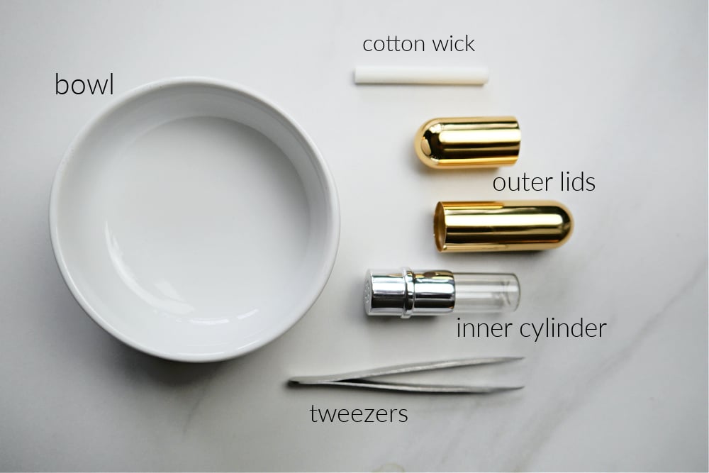 White bowl, tweezers and a gold inhaler taken apart.