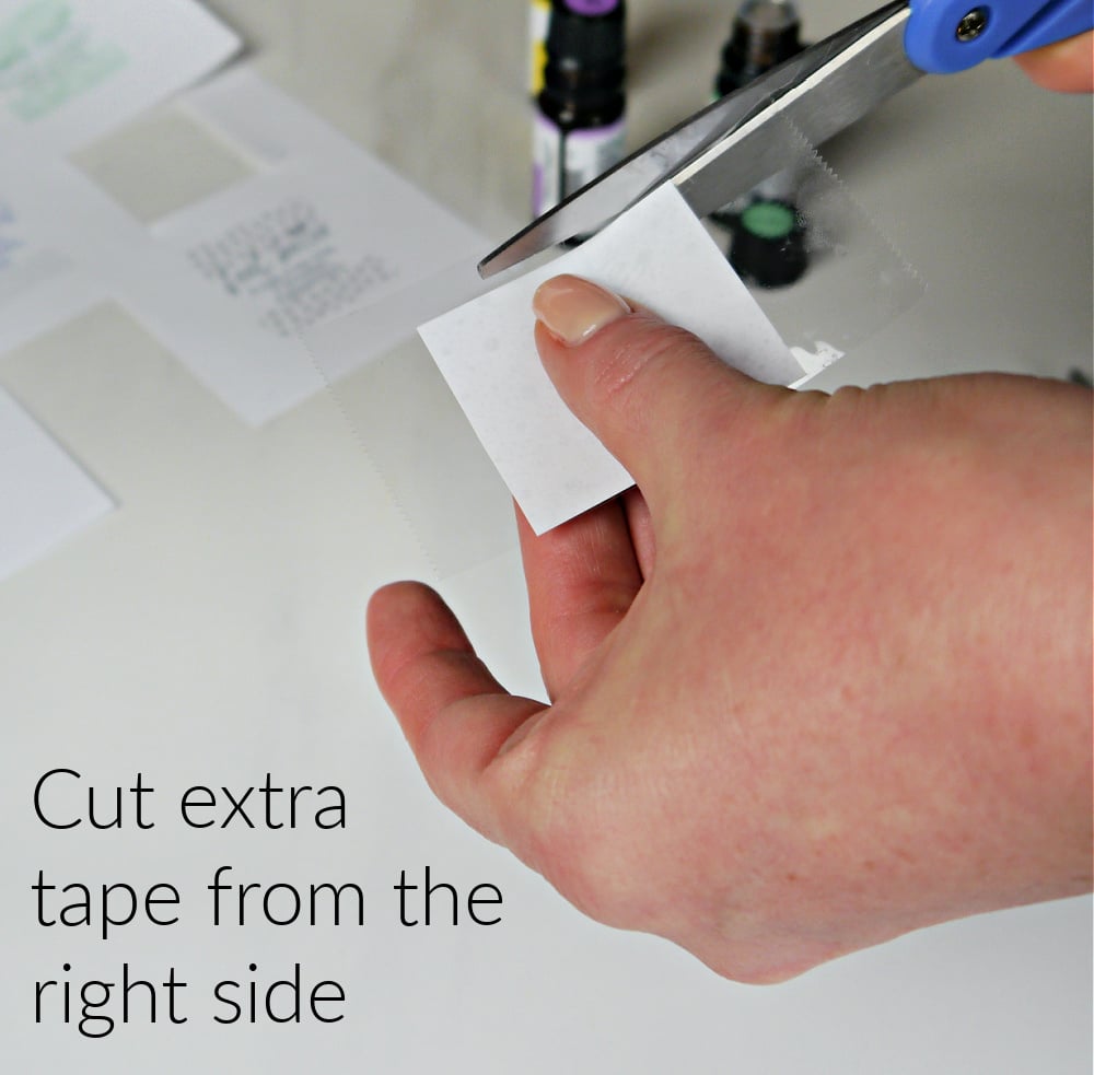 Hands cutting excess tape from the label.