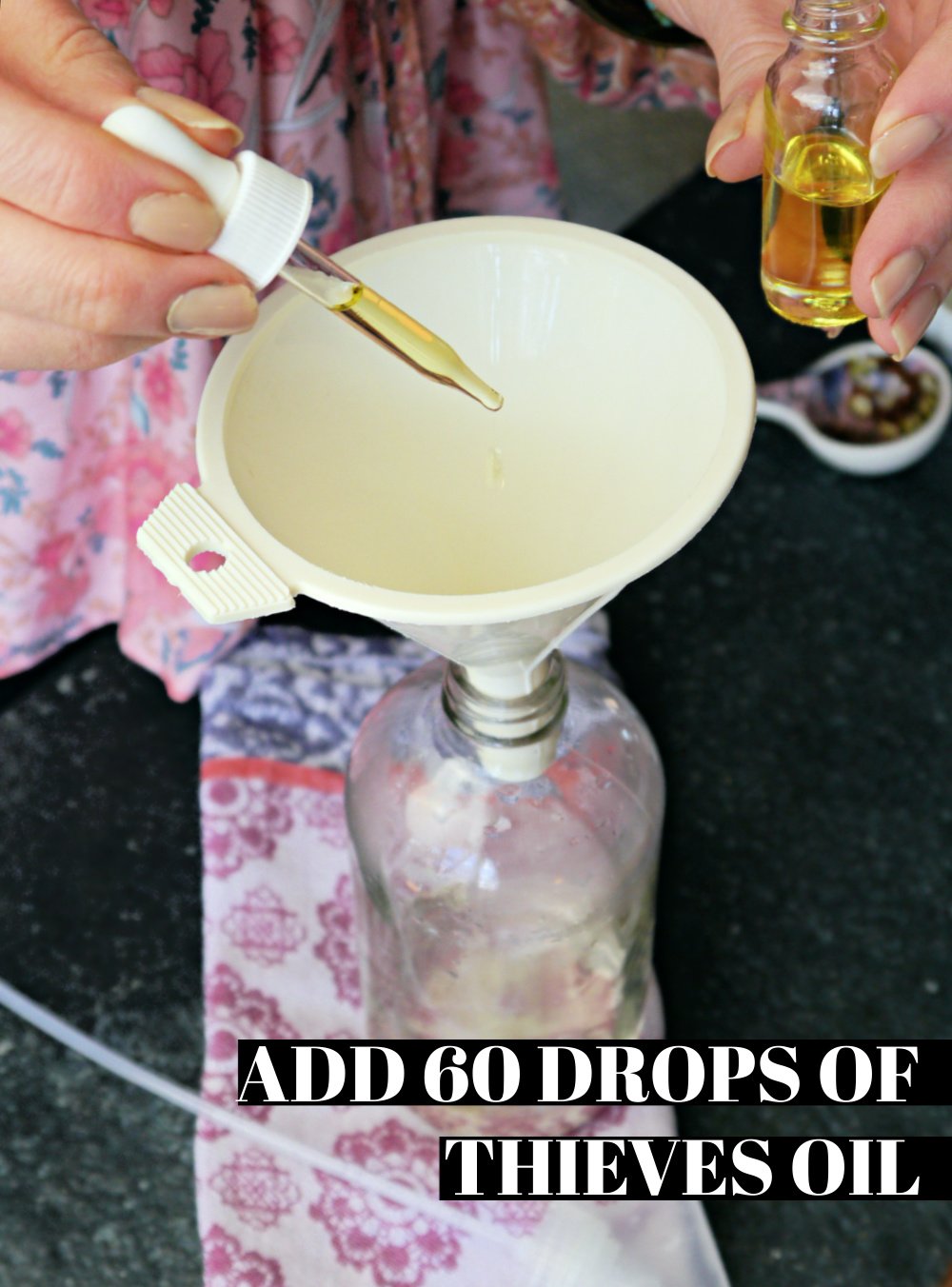 Hand dropping in essential oil in a funnel on a glass spray bottle.