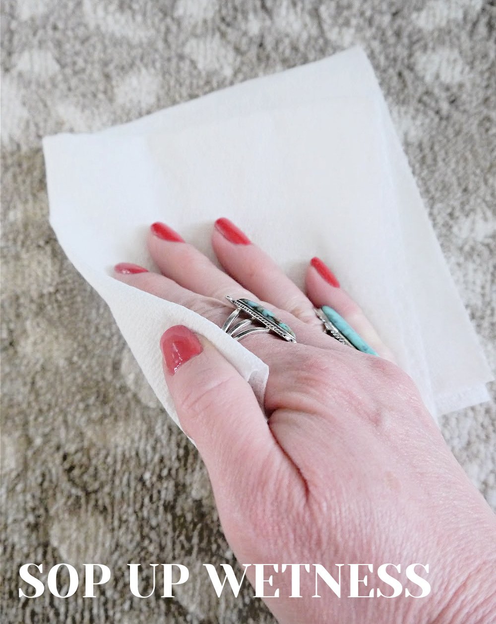 Hand sopping up wet stain with paper towels 
