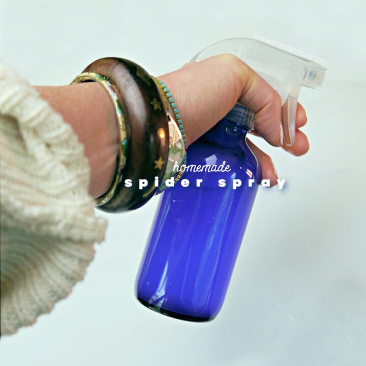 Hand spraying a blue glass bottle.